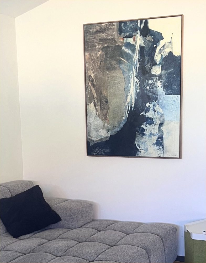 Échappée Bleue encadrée, présentée sur un mur clair au-dessus d’un canapé gris.